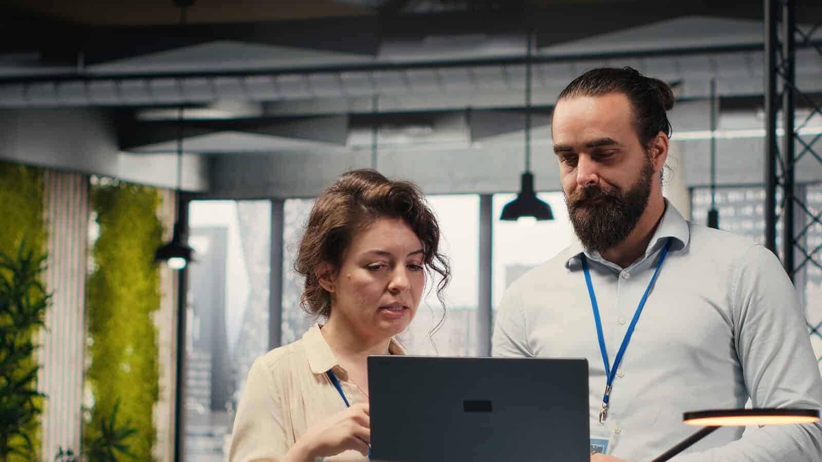 Business IT support discussion with consultants reviewing a laptop in an office