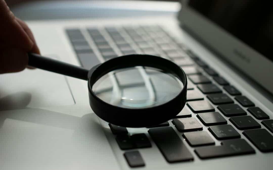 magnifying glass near gray laptop computer